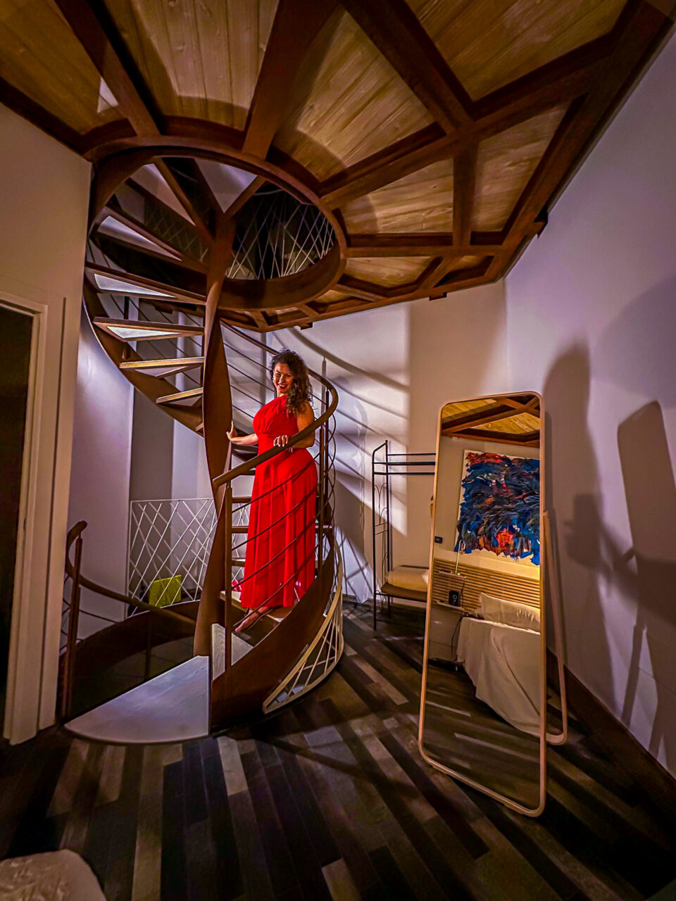 Foto di ragazza sulle scale con vestito rosso dentro un alloggio insolito italiano